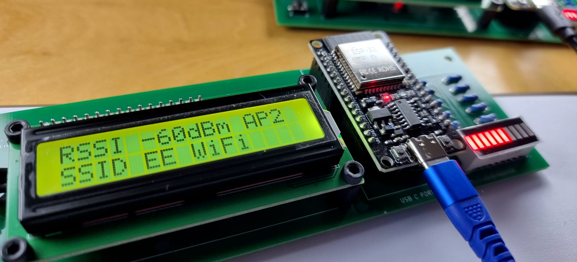 Spectrum One ESP32 WiFi activity monitor running standalone on USB power, showing RSSI −60 dBm on a 16×2 LCD with LED signal level bar. Photo: Jay J. Reszka